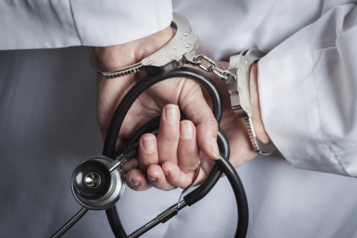 Female Doctor or Nurse In Handcuffs and Lab Coat Holding Stethoscope.